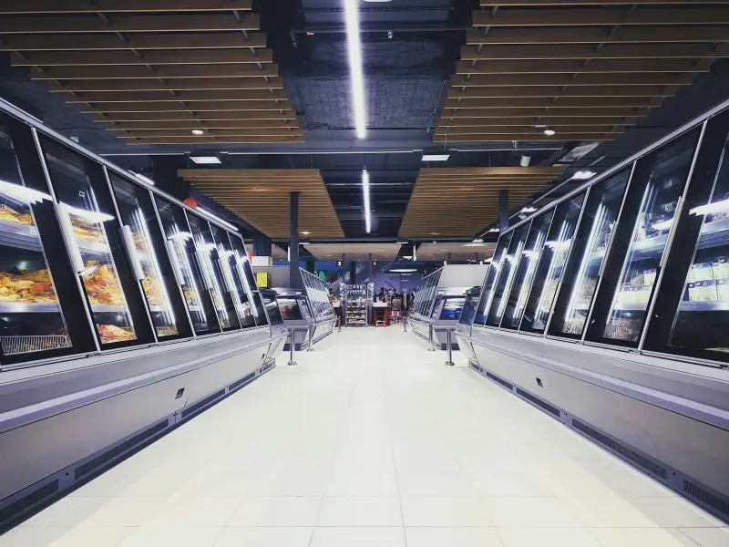 Supermarket aisle lined with refrigerated display cases