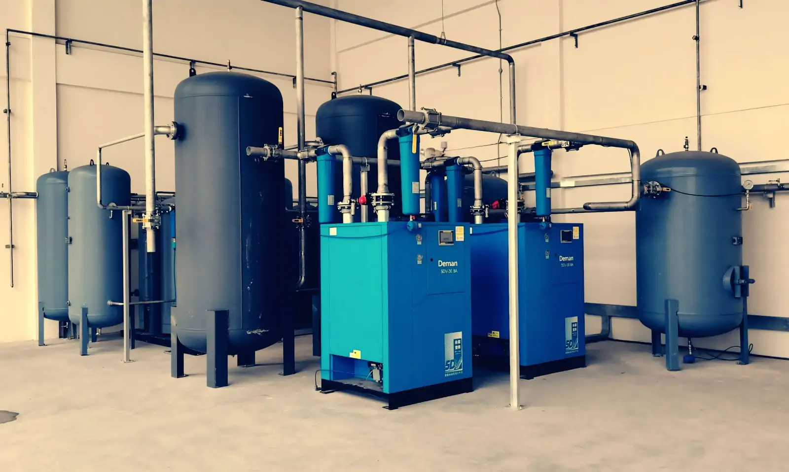 Industrial utility room with blue process vessels, pipework and packaged units